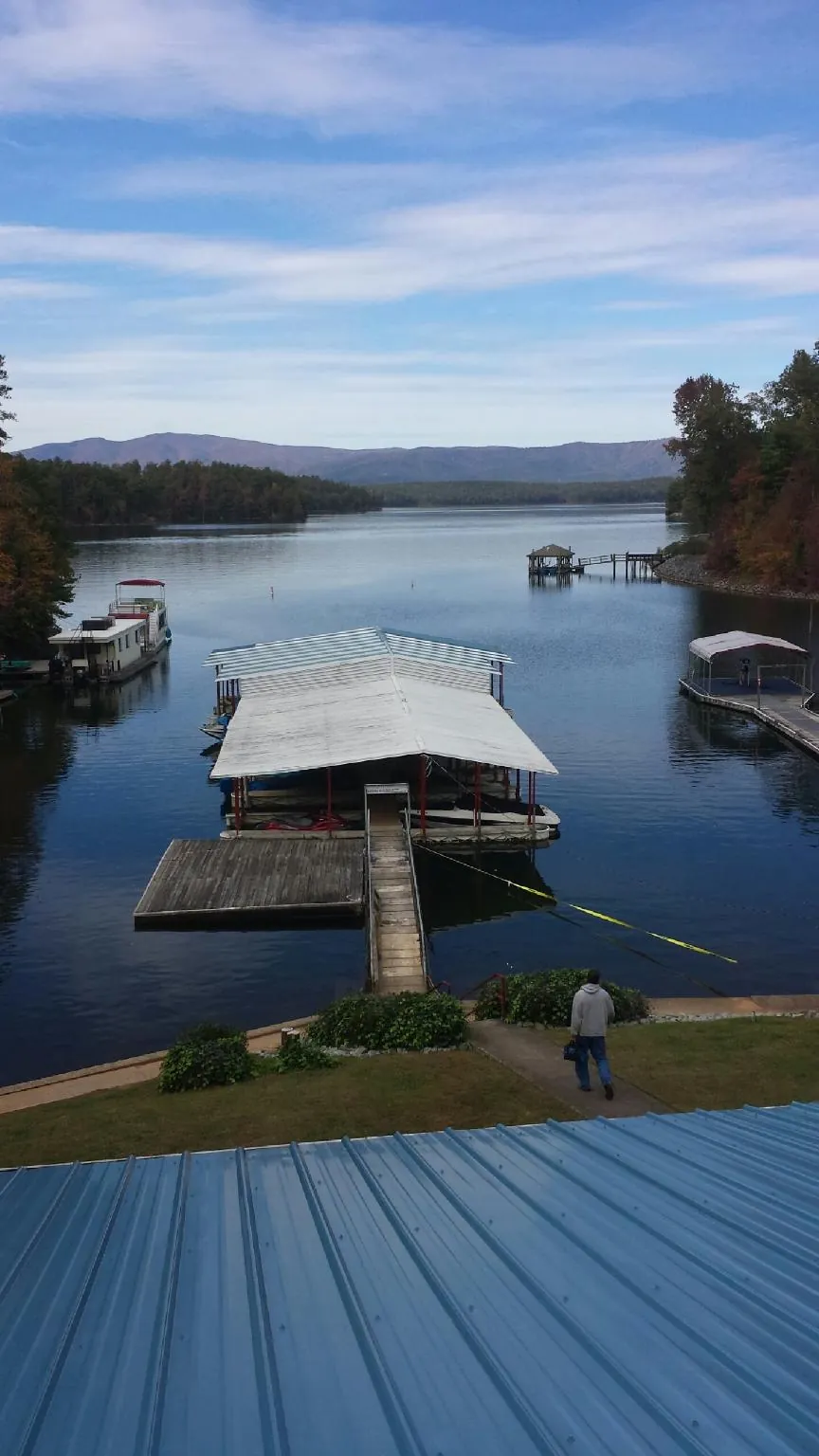 View across a lake from a newly installed blue metal roof in New London